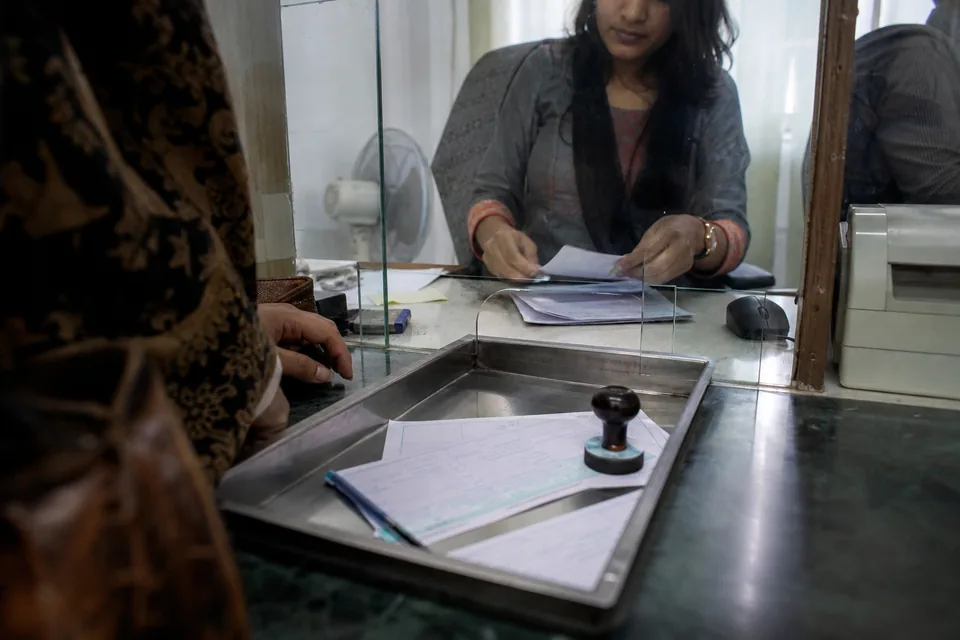 Bank teller window with transfer forms and a document tray