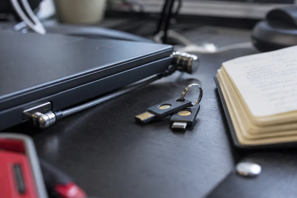 Hardware security keys and a laptop lock on a desk in a quiet office